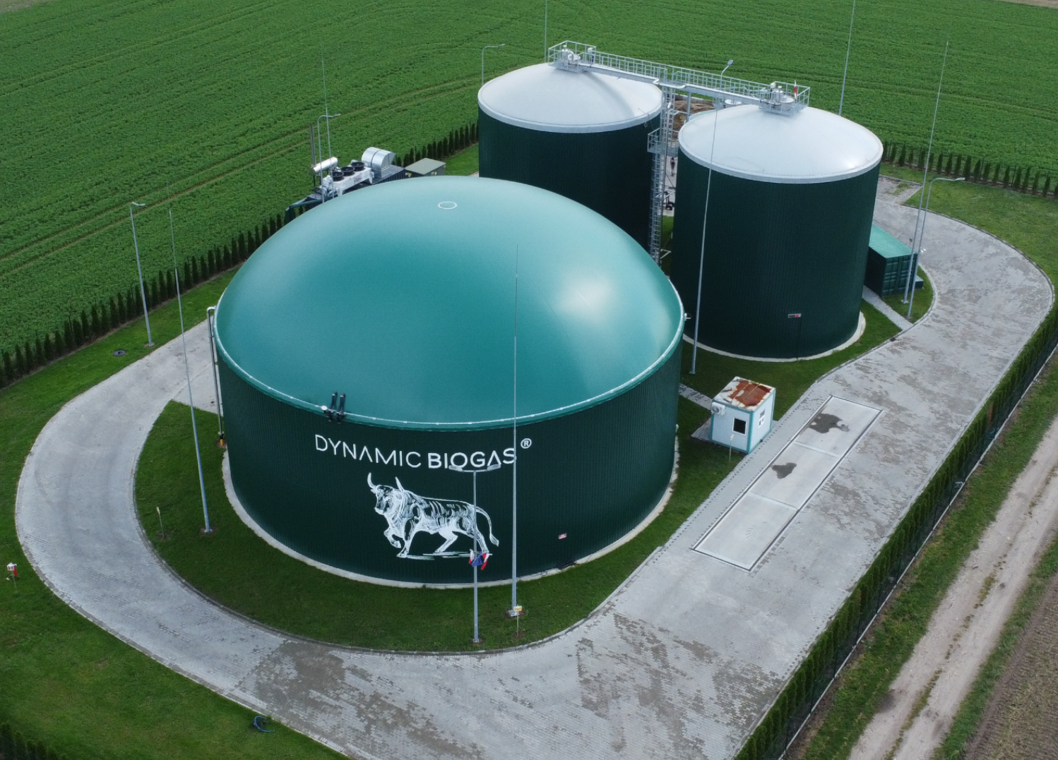 Specjalista rolnictwa na polu kukurydzy, w tle nowoczesna instalacja biogazowa i panele fotowoltaiczne